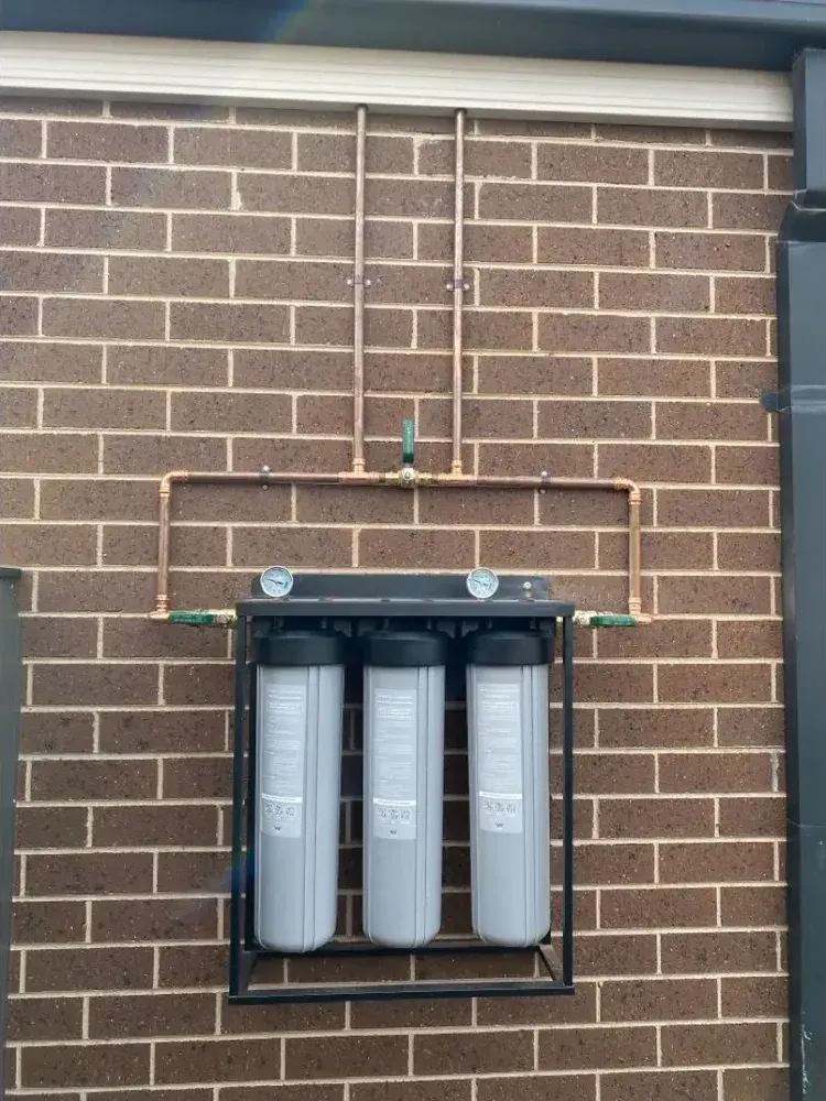 Three-stage whole-home water filtration system with copper pipework feeding a household water supply, installed by NJZ Plumbing