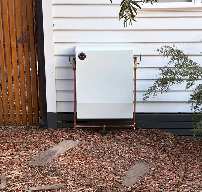 Whole-home water filtration system installed by NJZ Plumbing in Gisborne, mounted on a weatherboard home exterior with neat copper pipework