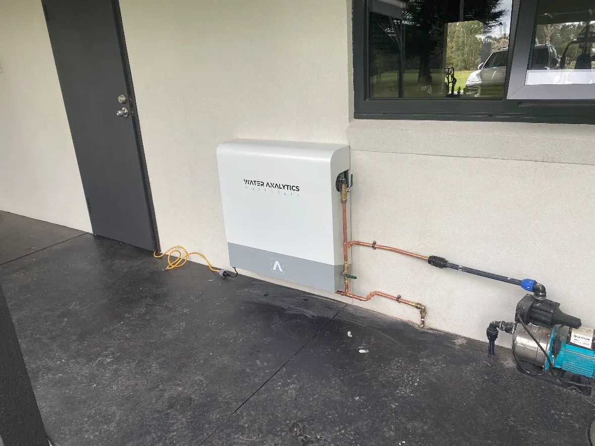 Tank water filtration unit installed by NJZ Plumbing on an exterior wall with copper pipework and pump